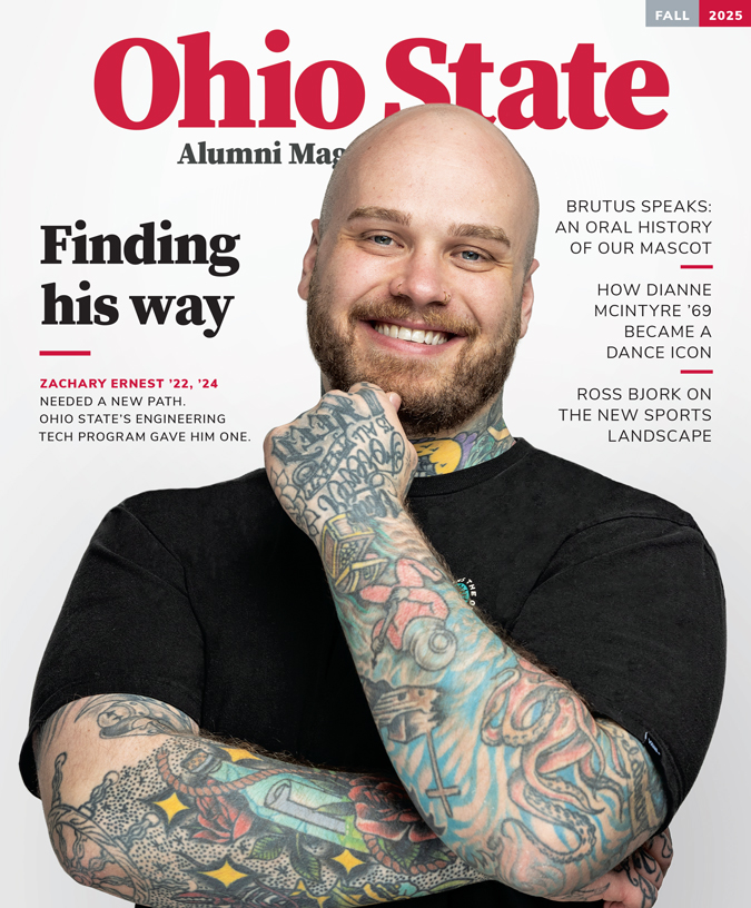 The cover of the Fall 2025 Ohio State Alumni Magazine shows alumnus Zachary Ernest sharing a friendly smile as he touches one hand to his chin. He wears a plain T-shirt, which sets off his blue eyes and colorful tattoos covering his arms and neck. Zack is a white man, in his early 30s, with shaved head and neat beard. The text says "Finding his way" and "Zachary Ernest '22, '24 needed a new path. Ohio State's Engineering Tech program gave him one.”