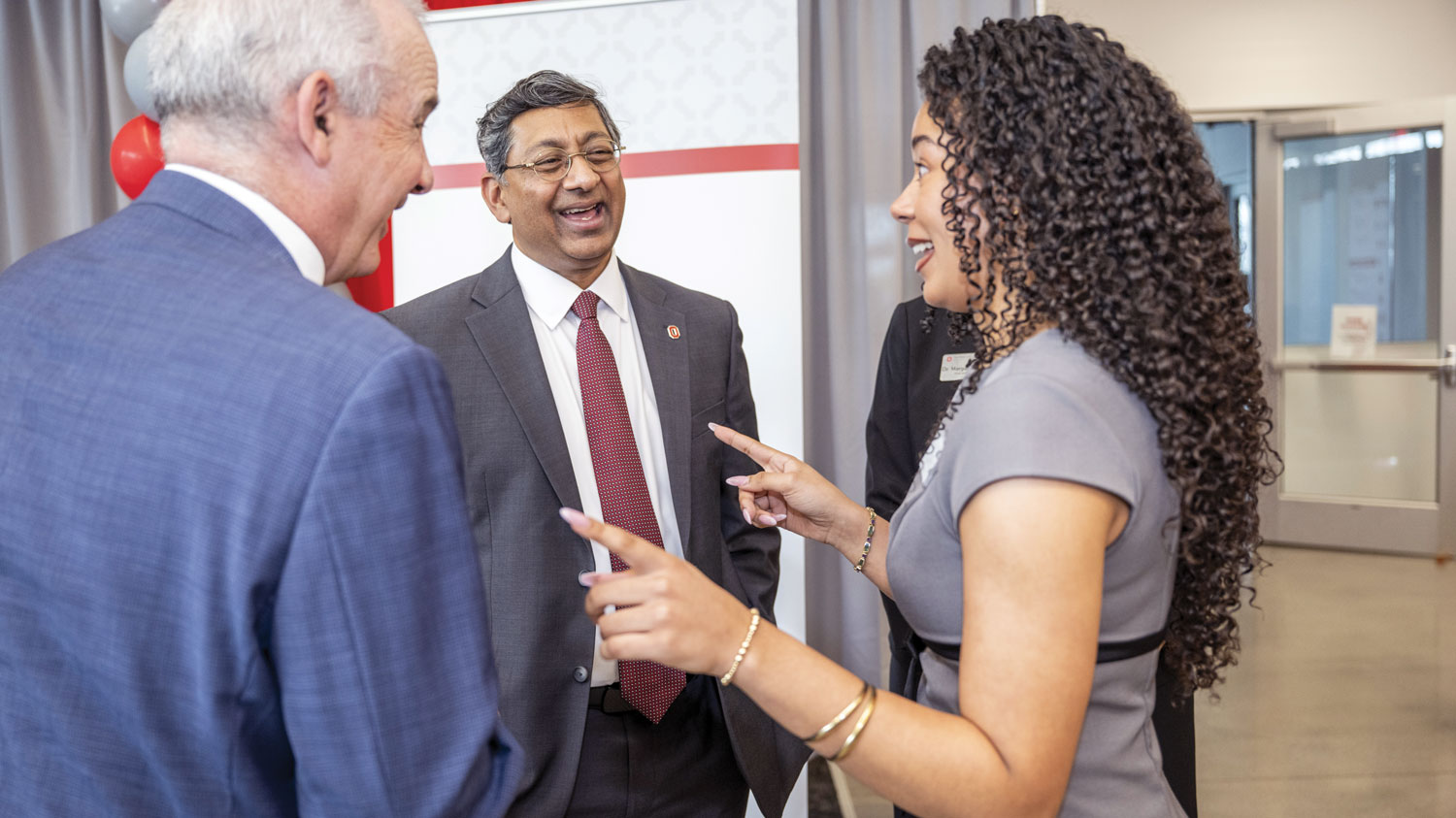 Bellamkonda laughs as he speaks with a young woman who is a student on the Lima campus and another man. All are dressed up and grinning