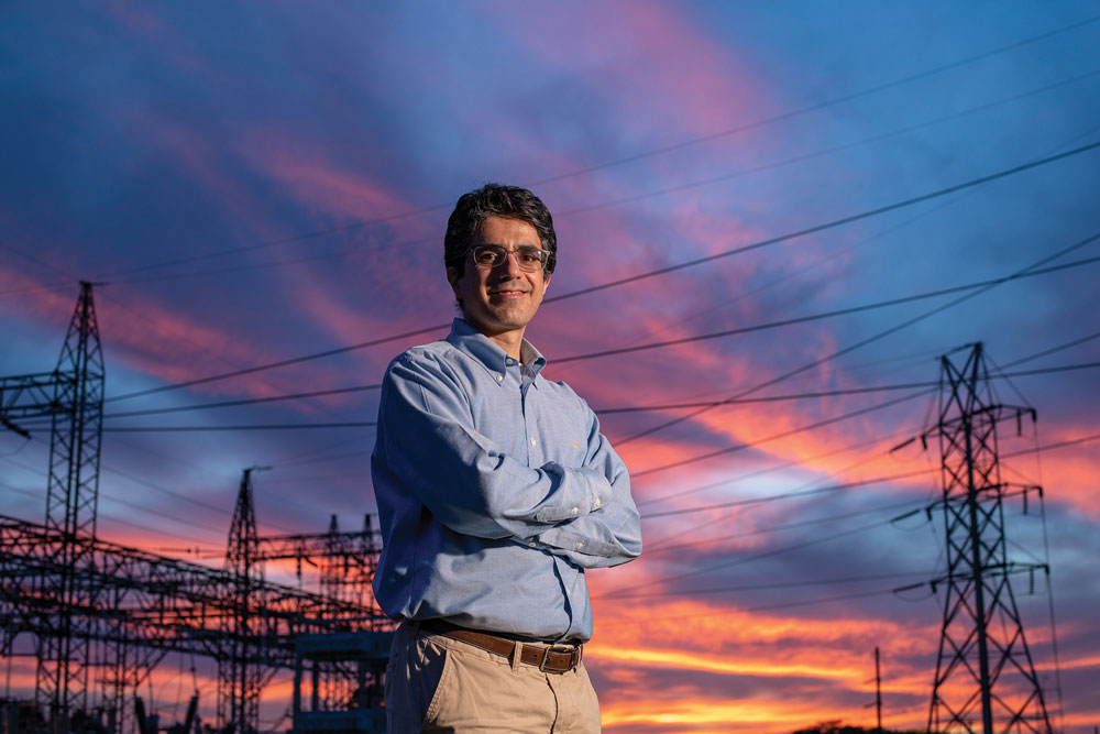 Abdollah Shafieezadeh smiles for the camera as he poses in front of a power grid in Columbus. The sky behind him is amazing--sunset colors highlight interesting cloud formations, so the black silhouette of the powerlines and towers stand out.