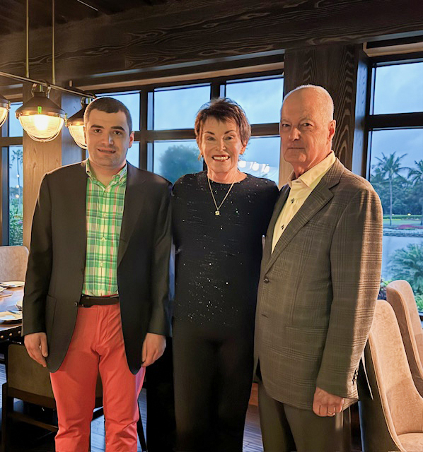A mother and father pose with their adult son.