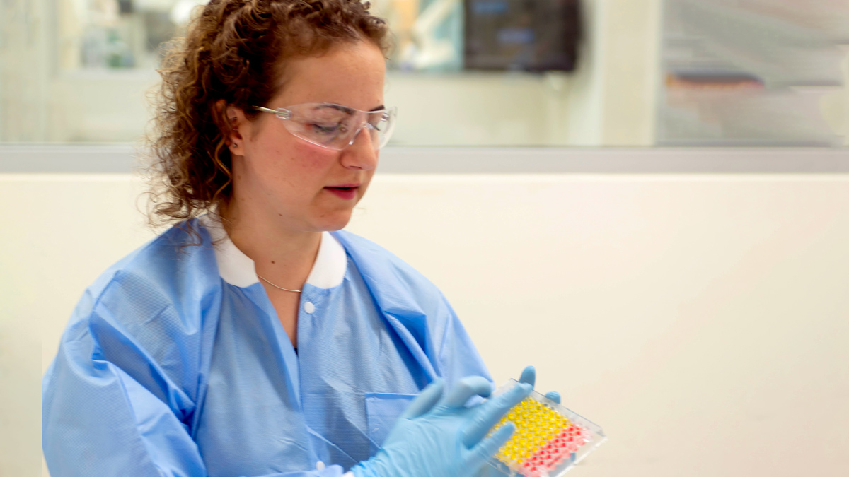 A woman in hospital garb works in a lab