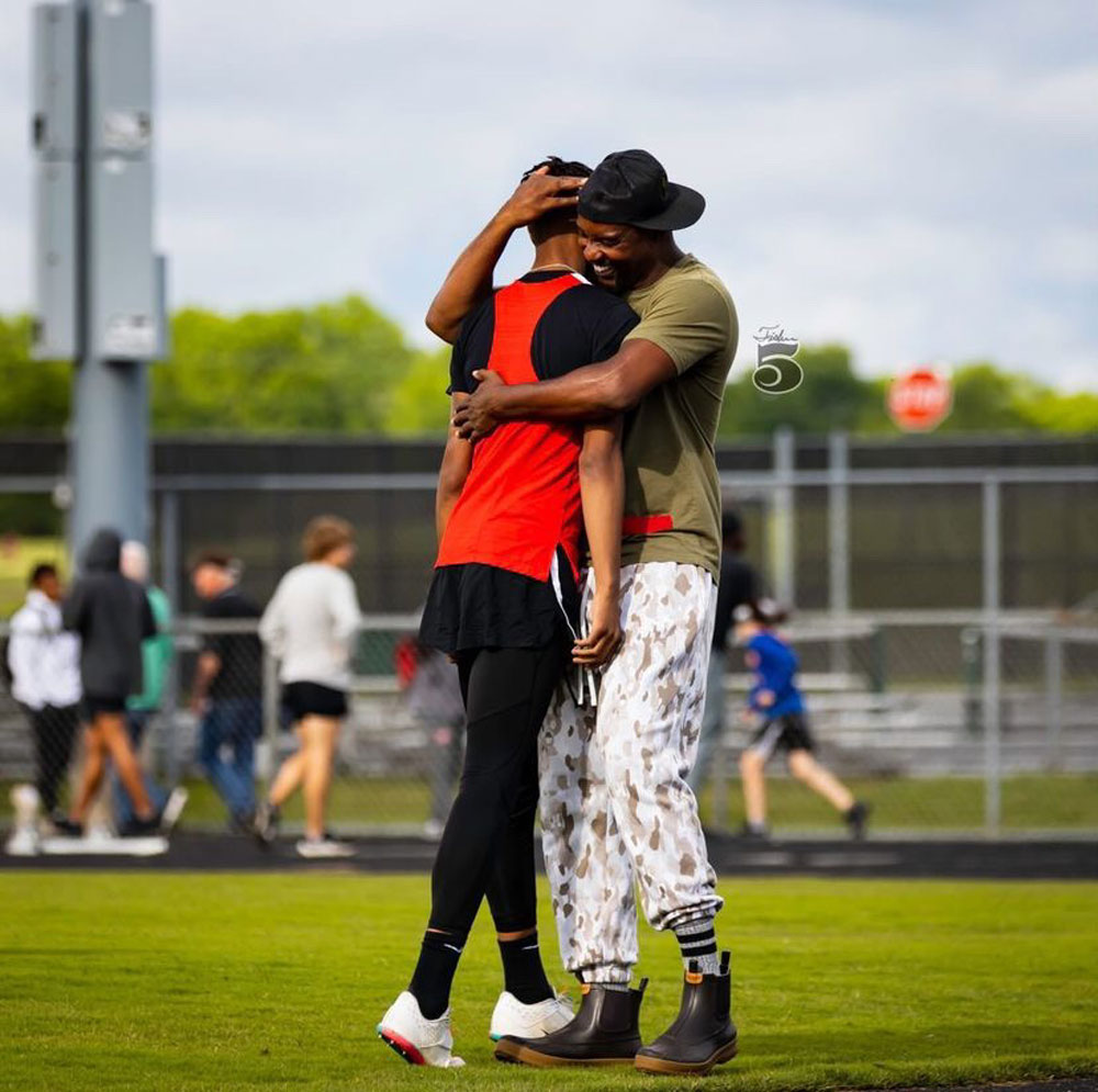 A father hugs his son on the field at a track and field meet the younger Winston was competing in.