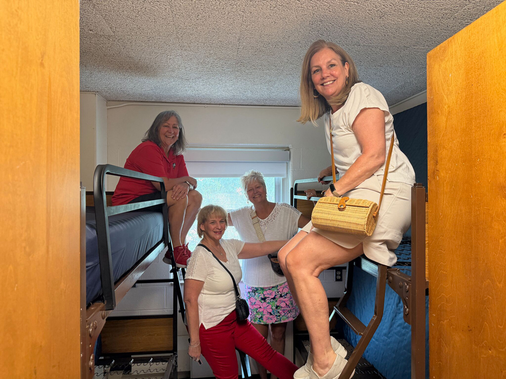 Molly Ranz Calhoun and three former dorm mates laugh as they crowd into a dorm room where they used to live. 