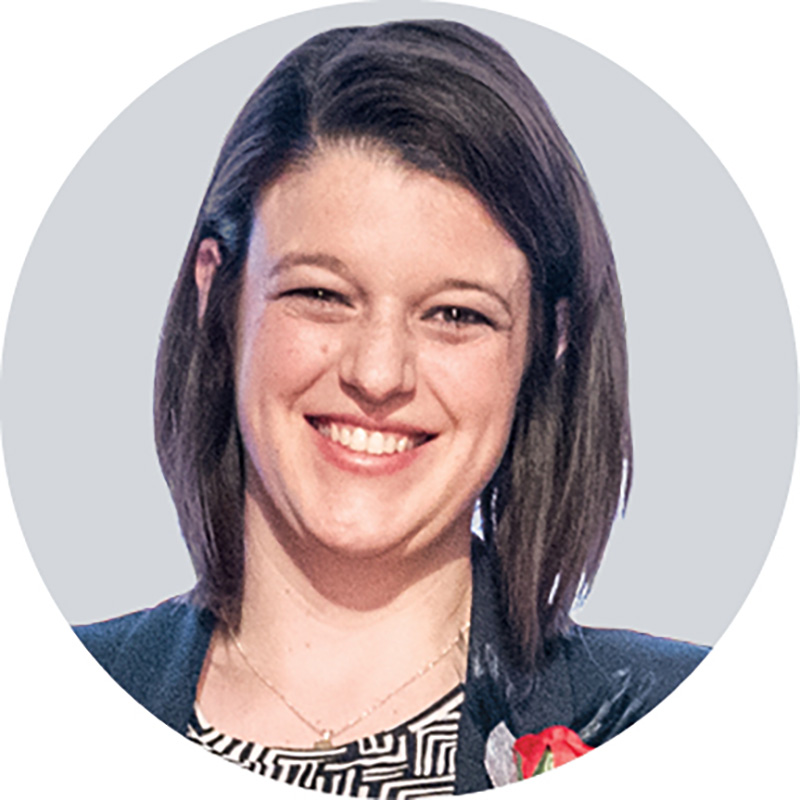 In this headshot, Tanya Nocera smiles after getting her award. She has dark hair and eyes and wears a suit coat over a patterned dress.