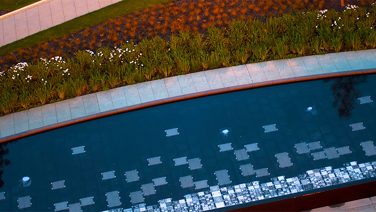 Aerial photo of a flower bed of red, green, and white plants next to a reflecting pool.