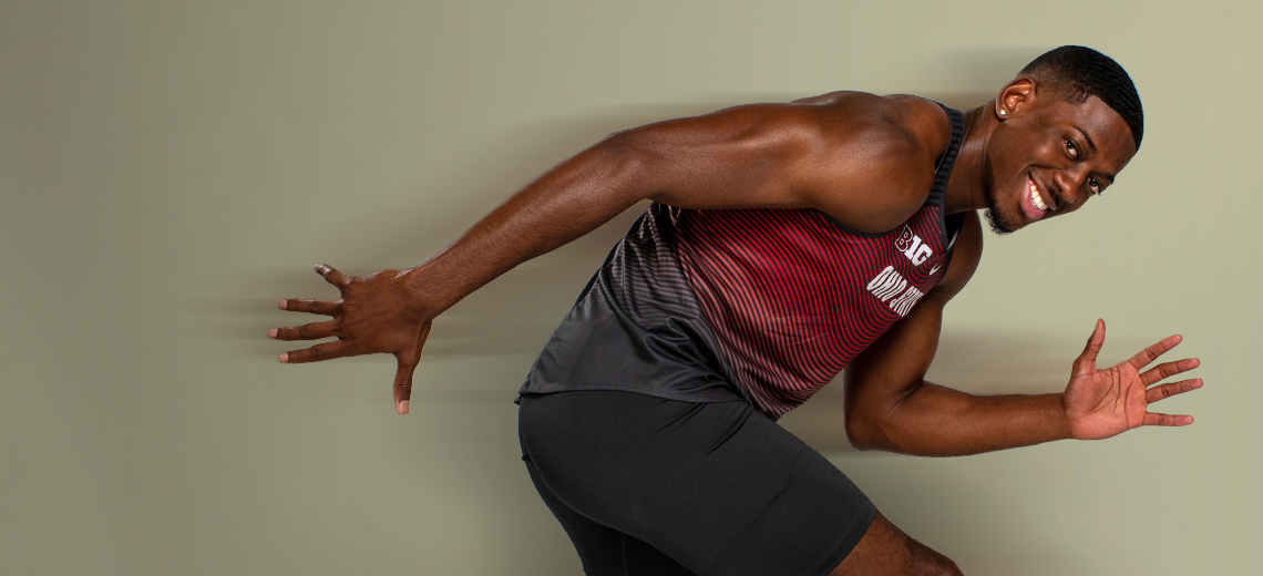 Nick Gray in Ohio State track uniform looks into camera and strikes a starting blocks pose