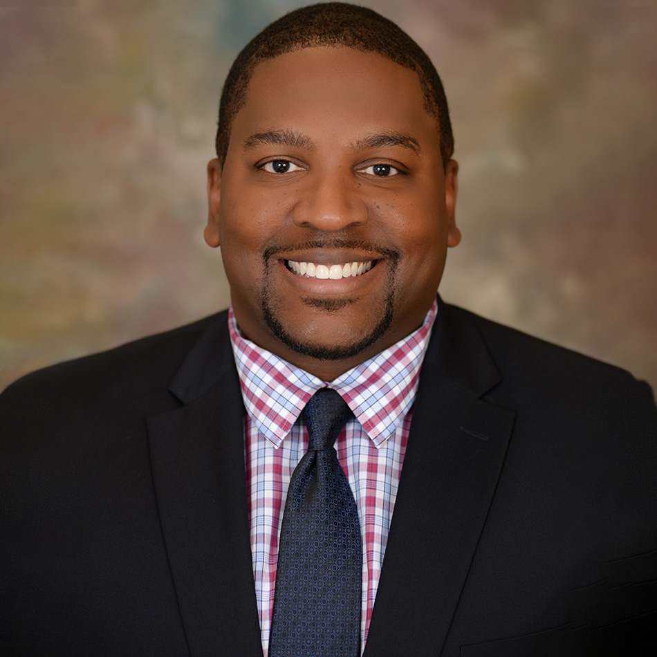 portrait of Vincent FLowers wearing a black suit and checkered shirt smiling