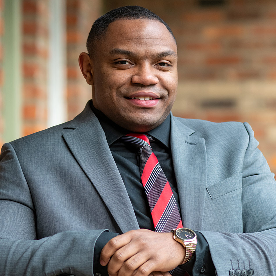 portrait of Ke'von Huguely wearing a gray suit and red striped tie