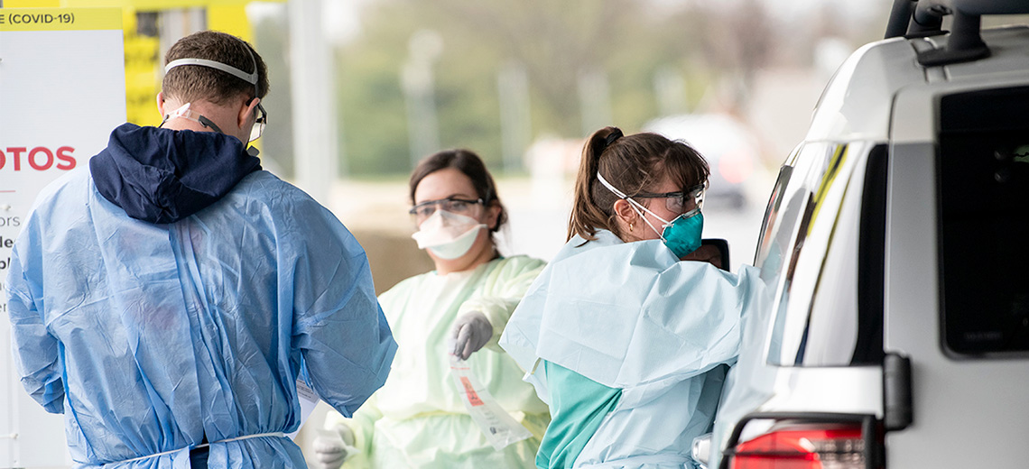 Health care workers handle COVID-19 testing at a drive-thru test site
