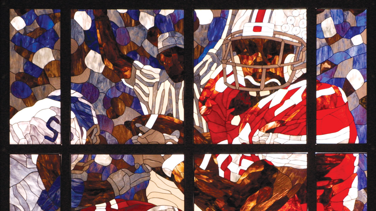 A portion of a stained glass window shows a Buckeye player rushing with the football
