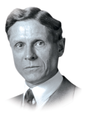 A man with waves styled into his hair and wearing a suit looks as if he is carefully posing for this old portrait.