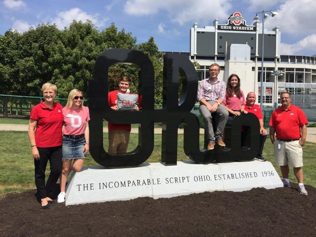 People standing around a black script Ohio statue