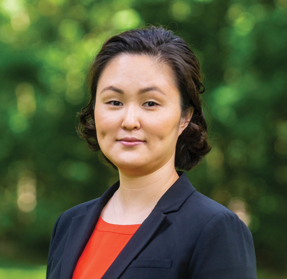 Sophia Jeong softly smiles in this portrait. She's a woman of Asian descent with curled hair and she wears a blazer.