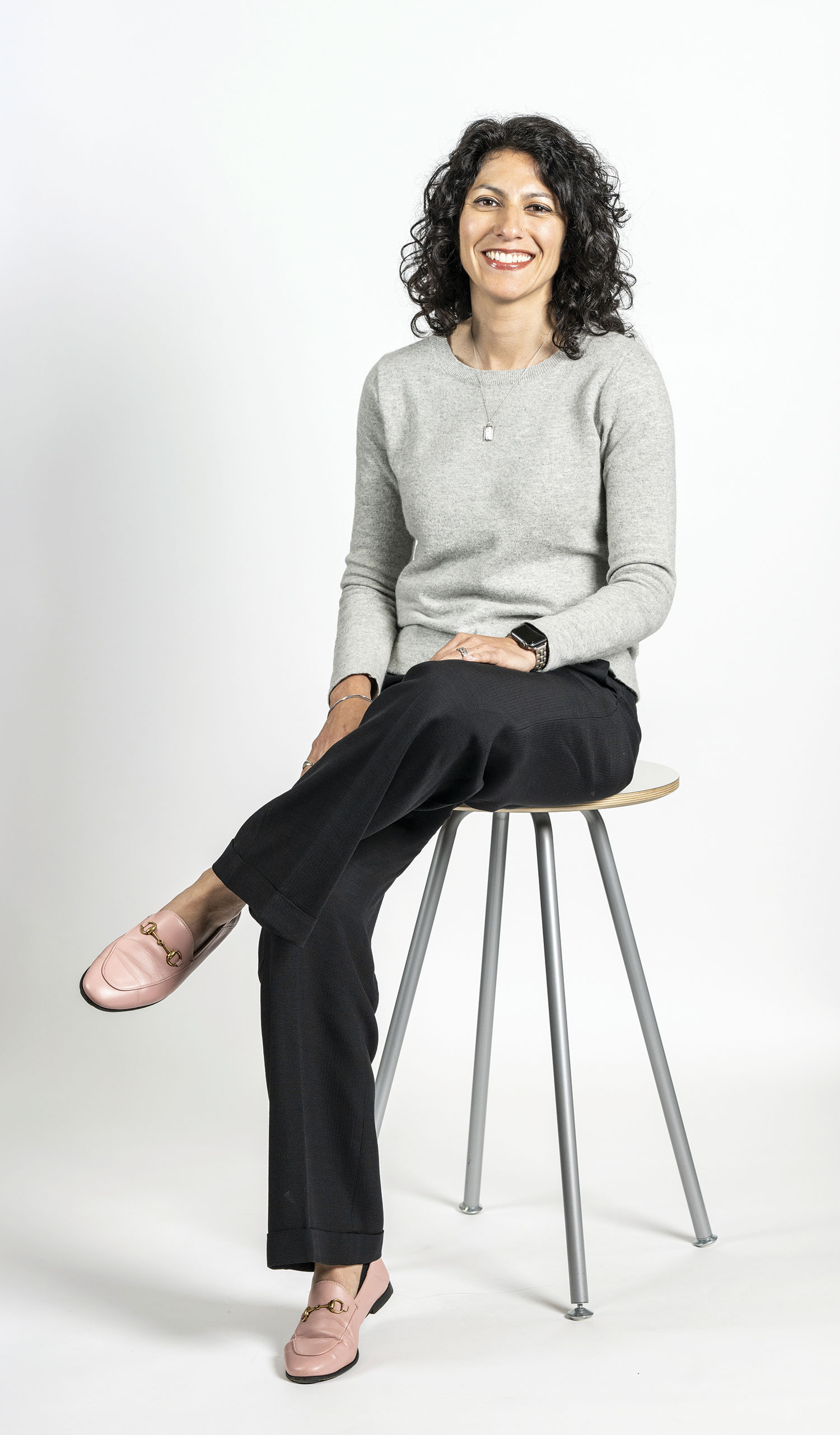 Tahira Rehmatullah smiles as she poses for a photo. She's a pretty woman with curly hair and a big smile.