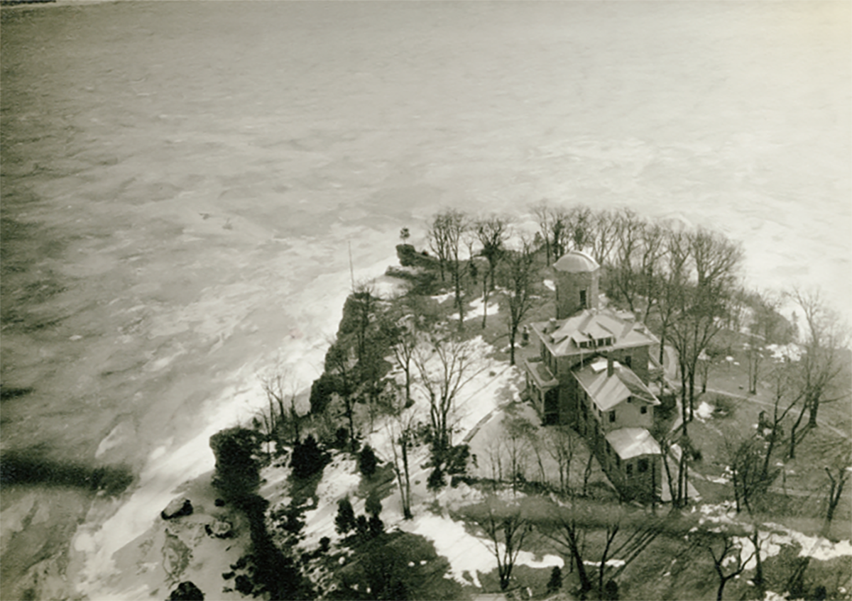 A sky view of the back of Cook Castle on Gibraltar Island shows the building's rounded tower, the island's cliffs and  a lot of Lake Erie