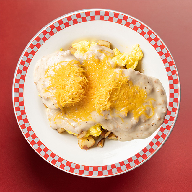 A smothering of gravy and finely grated cheese covers most of the food on the plate, but some eggs and potatoes peak out at the edges.