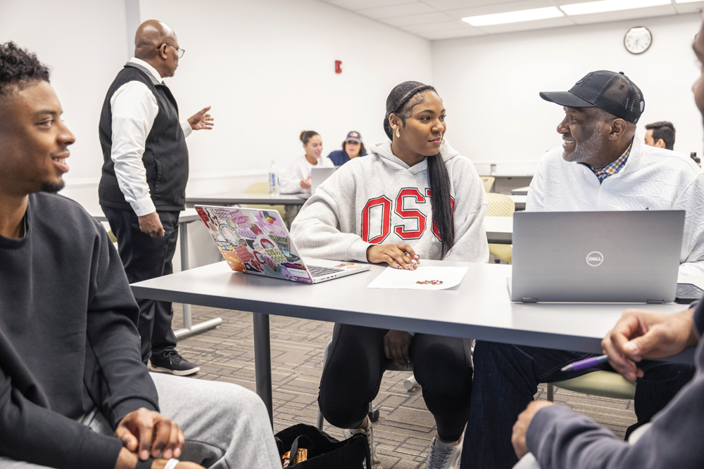 Faith and Keith Hunter smile as they chat while sitting next to each other in class.