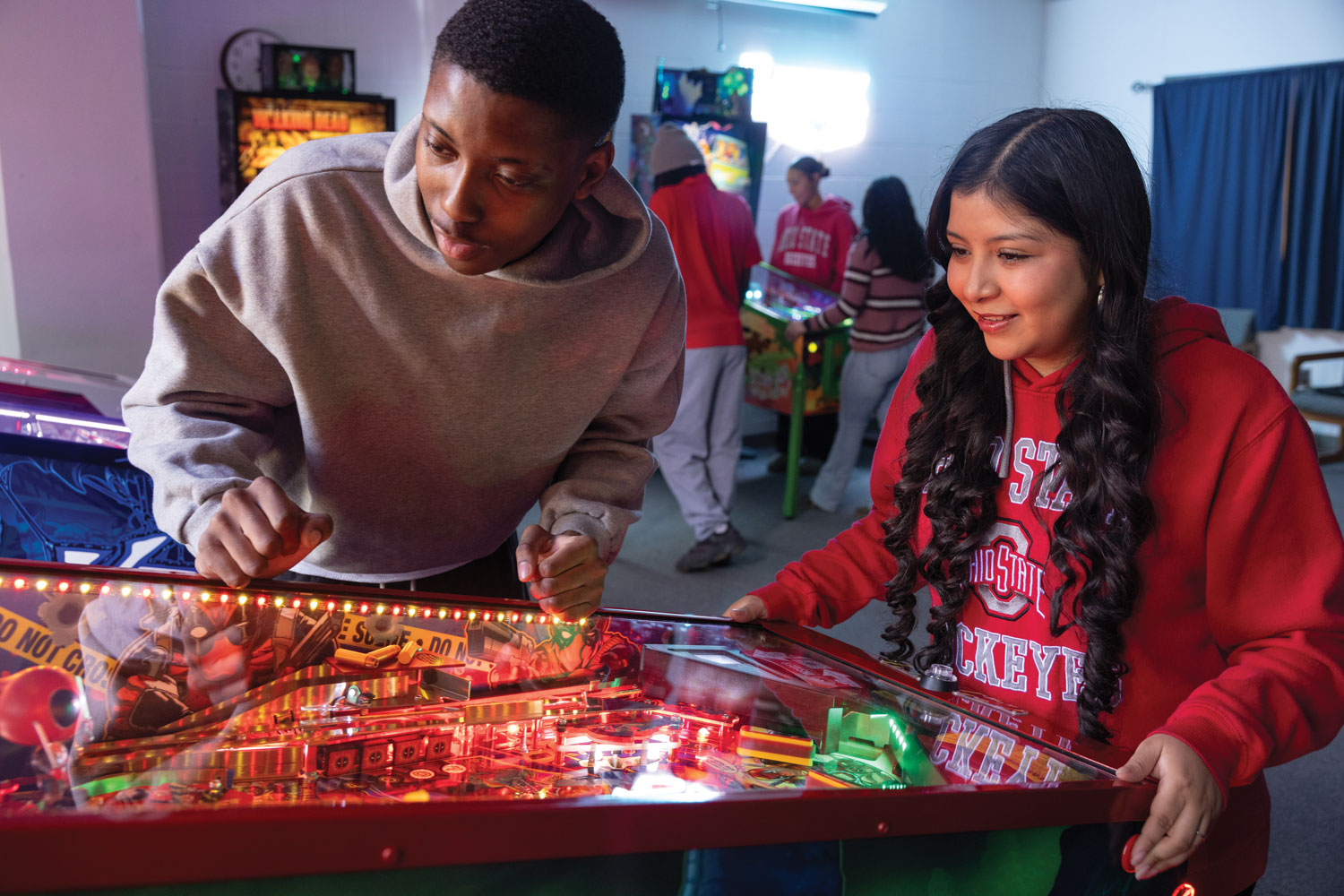 A pair of students have fun playing pinball at the Electric Playground.