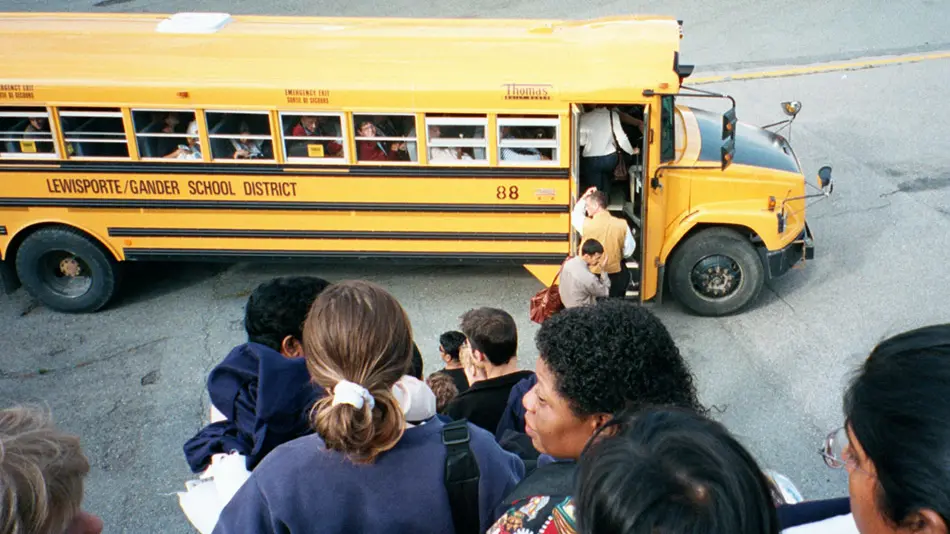 people walk down stairs towards a school bus