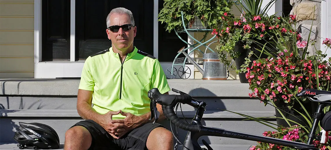 Man with sunglasses sitting next to a bicycle
