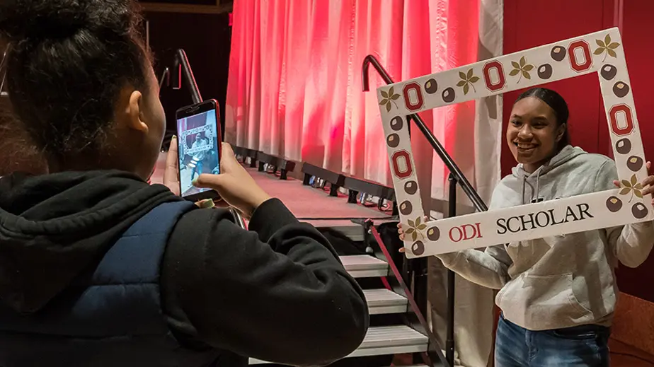 girl takes photo of another girl holding a picture frame