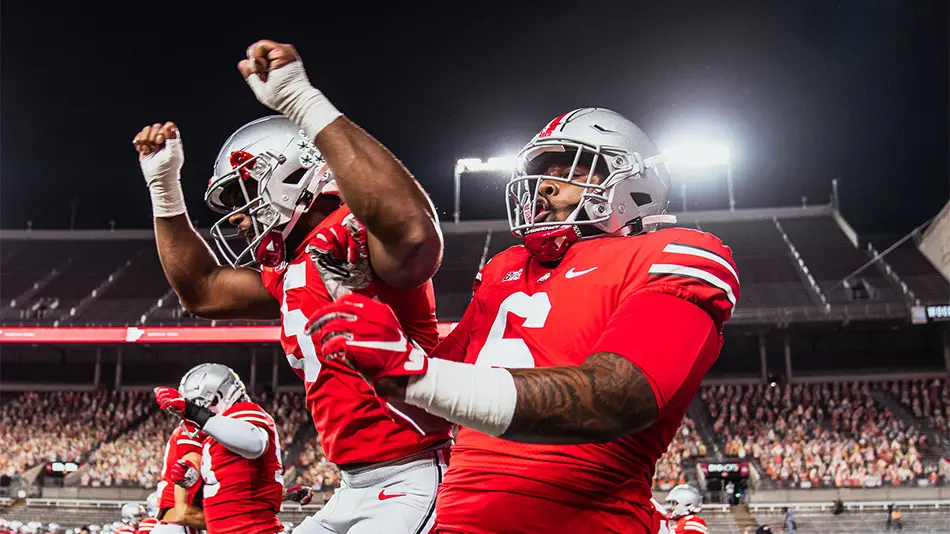 Garrett Wilson and Jameson Williams jumping and celebrating under the stadium lights at Ohio Stadium