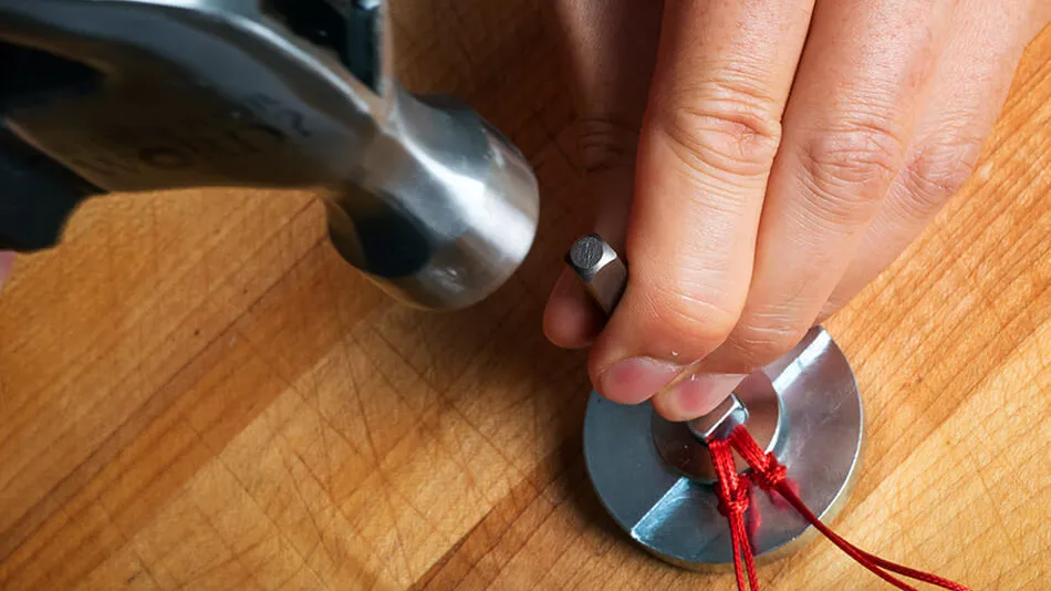 Photo of hammer hitting stamping tool over a washer