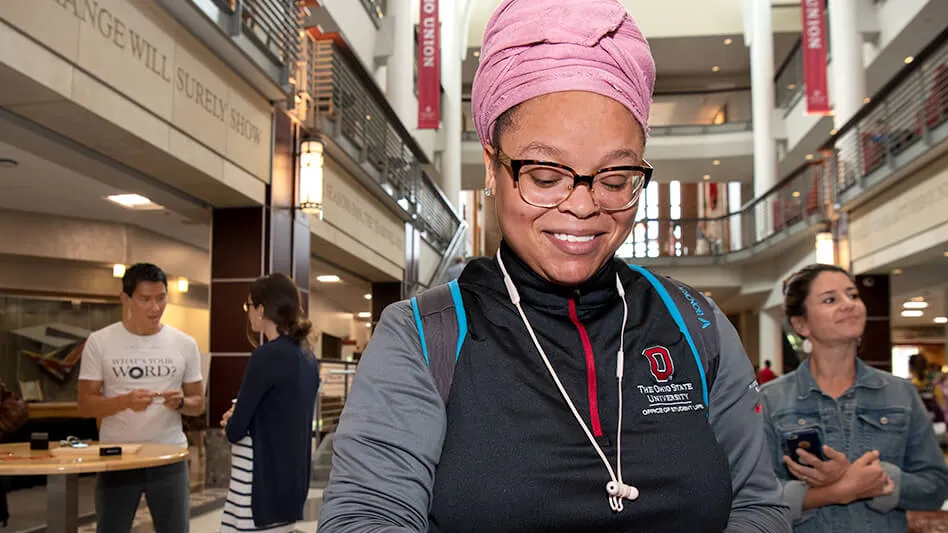 Woman in pink headwrap with glasses looking at washer bracelet on her arm