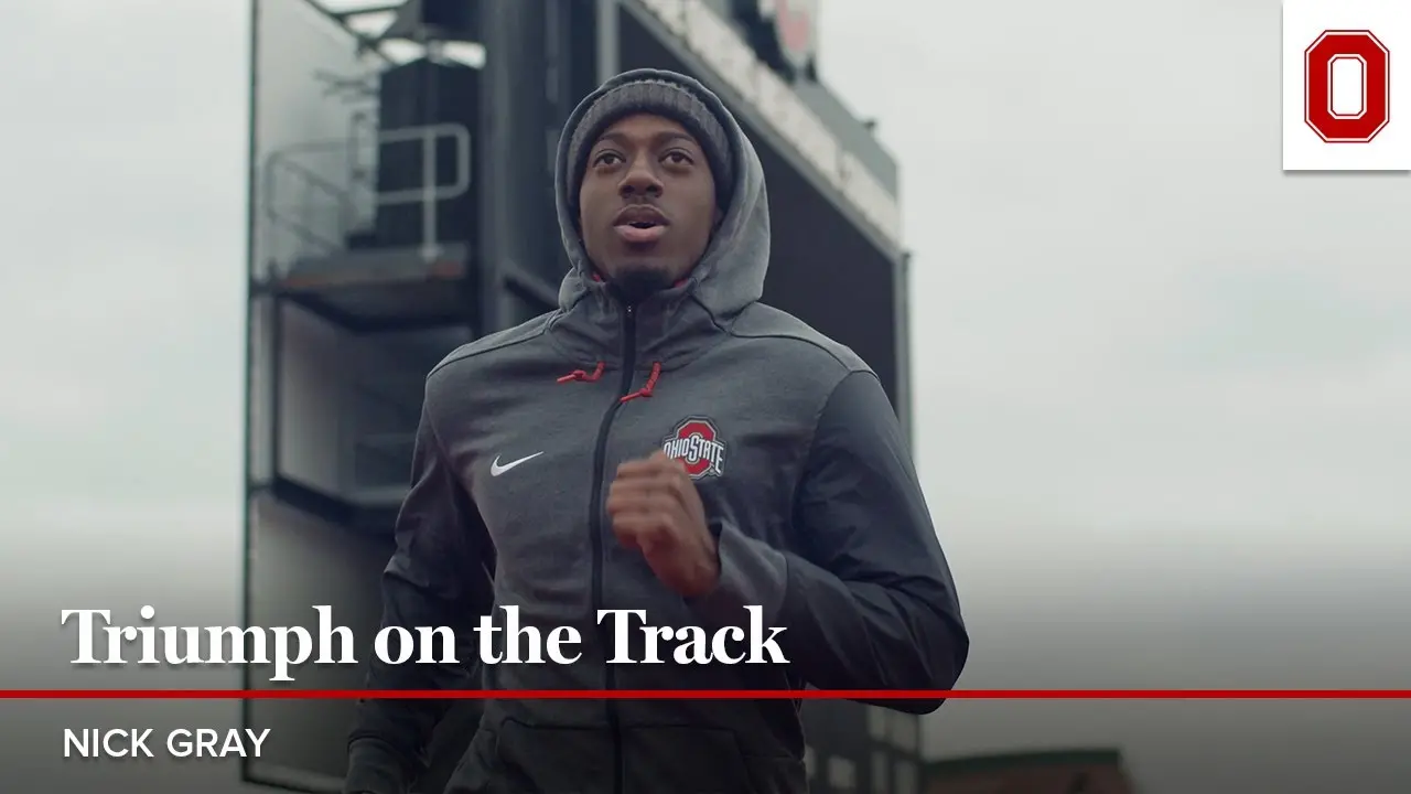 Nick Gray running outdoors with a gray OSU jacket on and his hood up