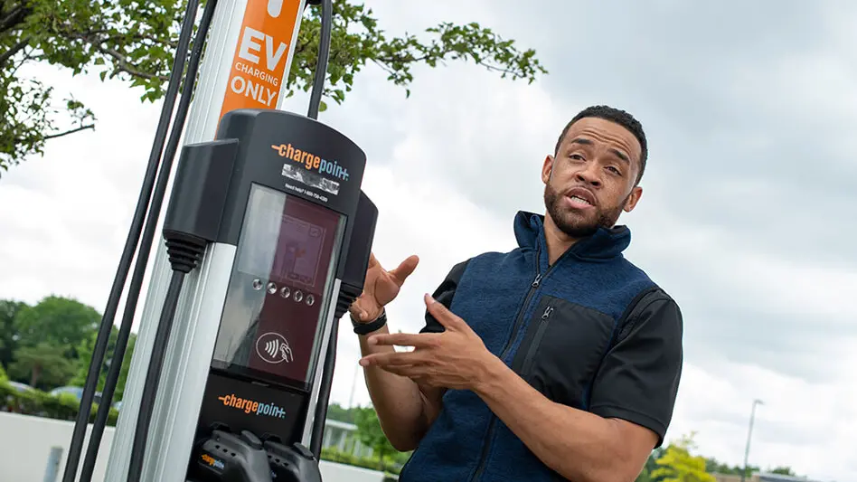 Charles Muse standing next to a vehicle charging station