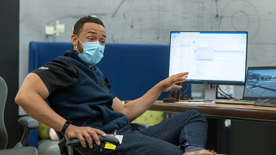 Charles Muse at his office gestures toward computer