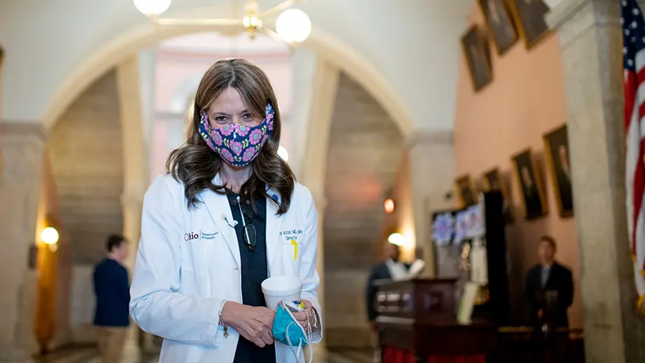 A smiling woman wearing a surgical mask