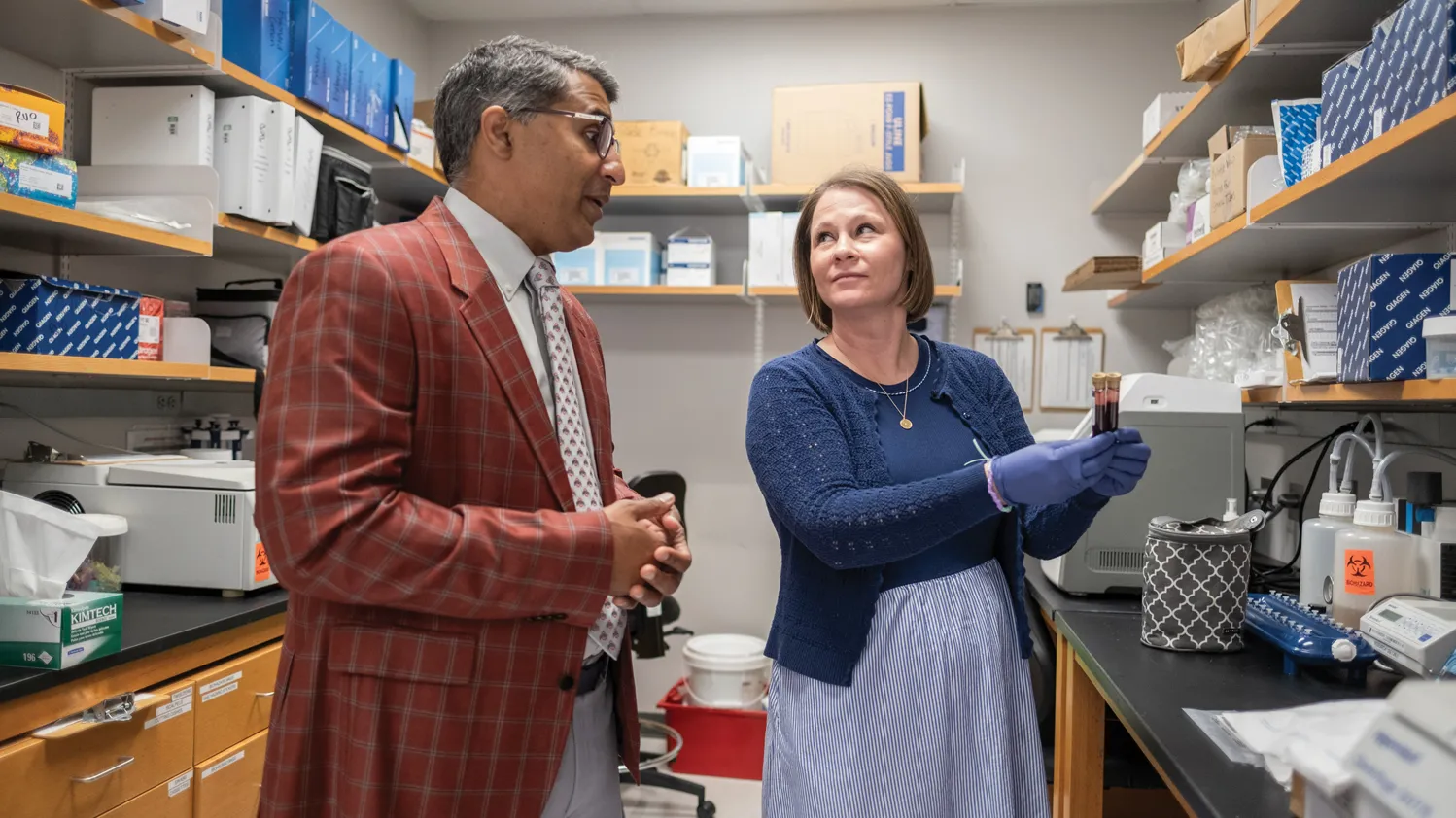 Roychodhury and Julie Reeser confer about blood samples. She holds two capped test tubes.