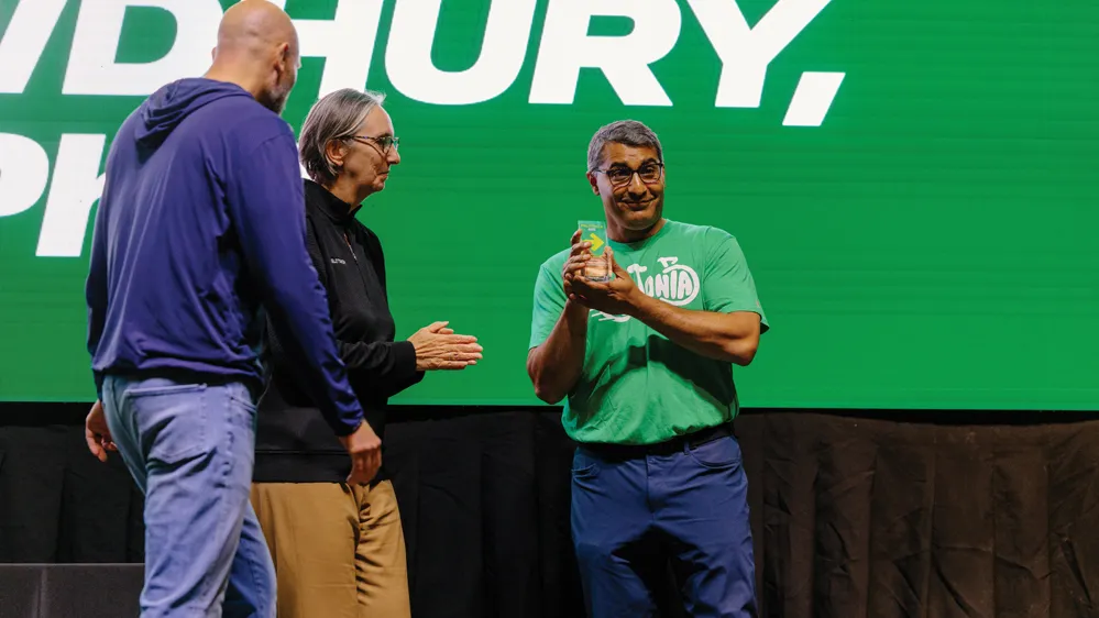 Standing on stage at Pelotonia, Roychowdhury shows the crowd his glass trophy, awarded for being named researcher of the year