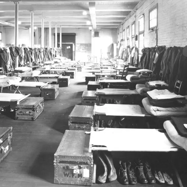 Black and white archival photo of a bunk room with rows of beds.