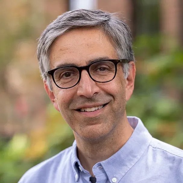 A smiling man with glasses poses for a photo. He has graying hair and an expression that says he's a good listener.