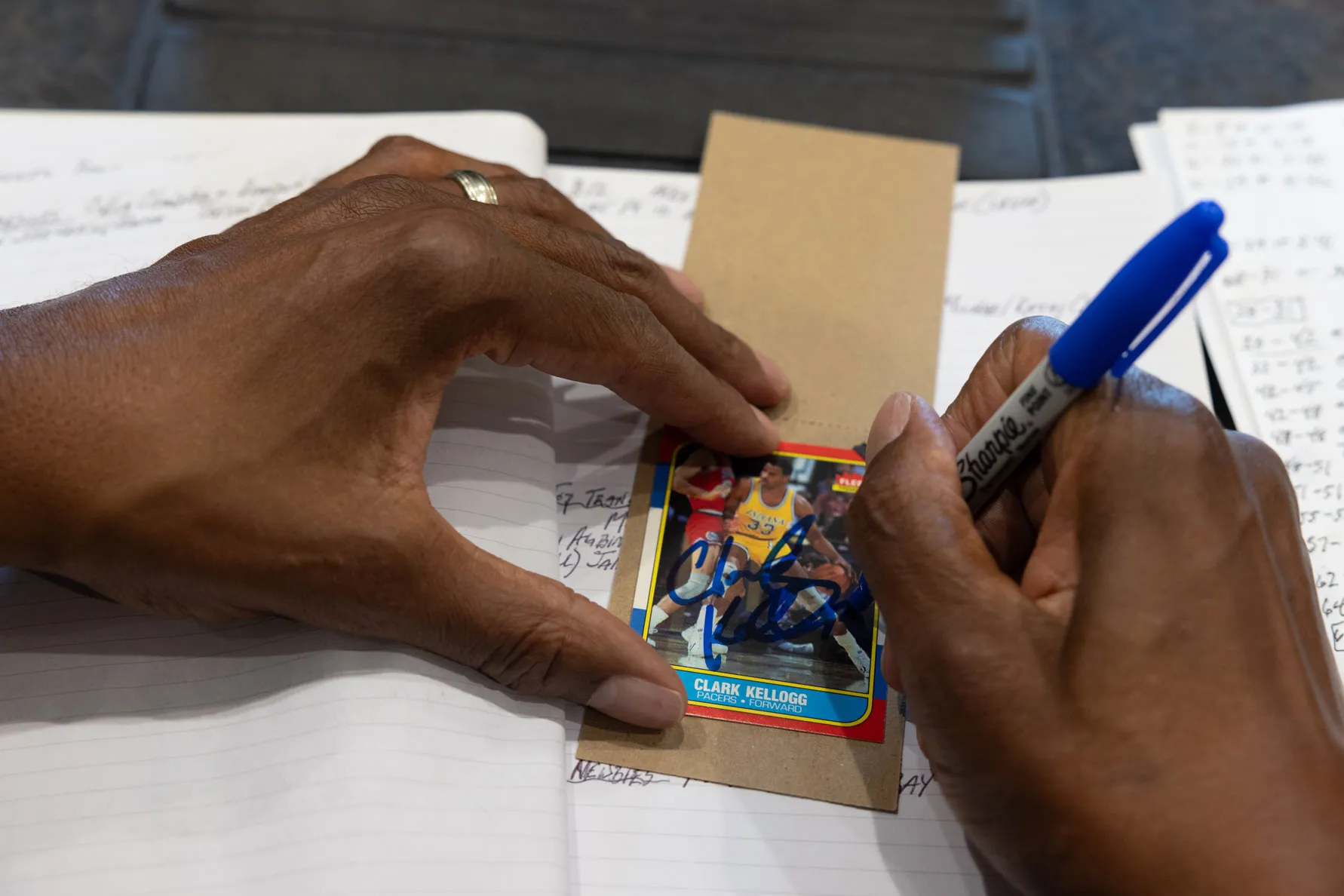 Kellogg signs a basketball card from his playing days