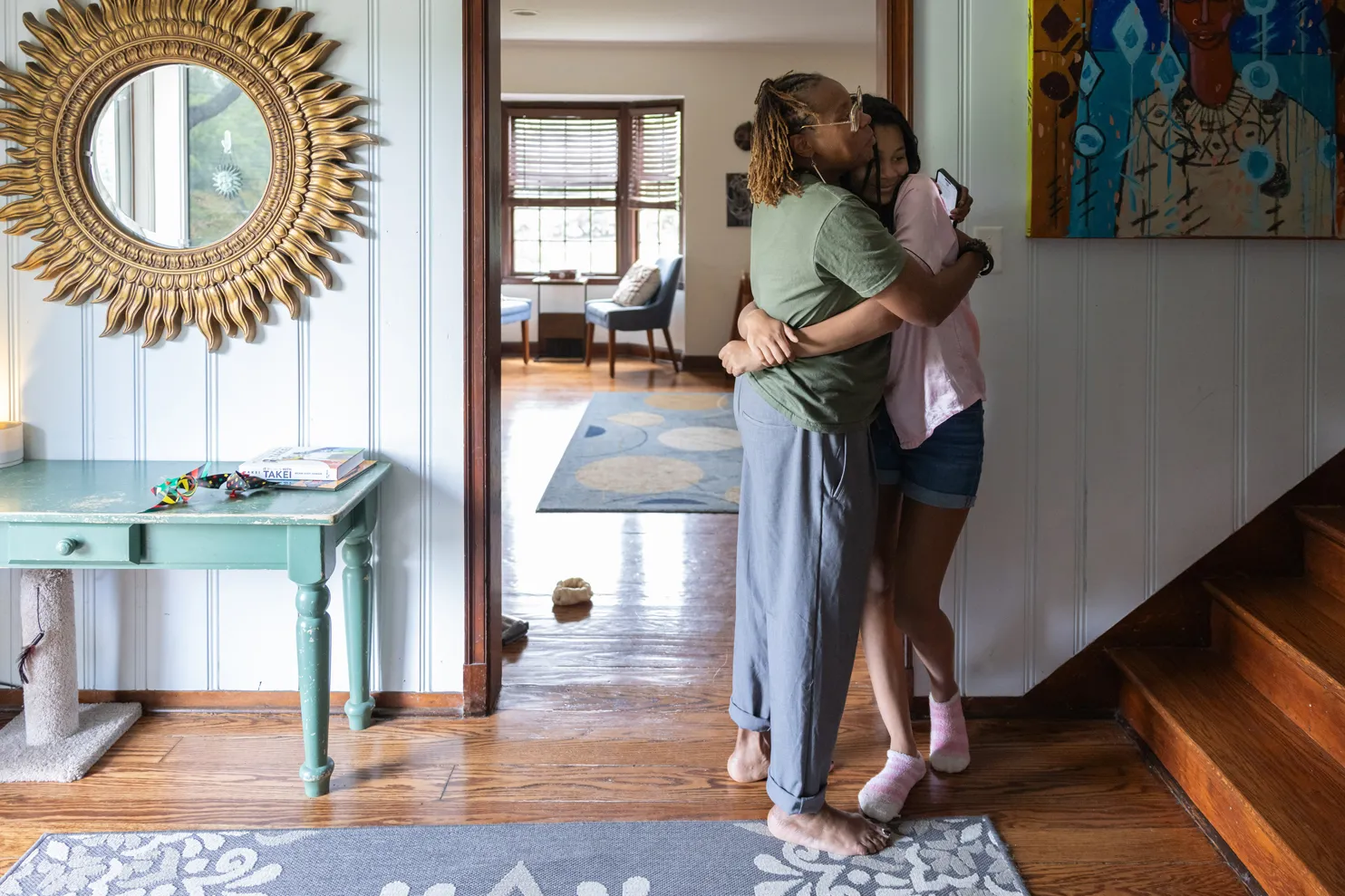 Sunami hugs her teen daughter in their beautifully decorated home. Her daughter is smiling.