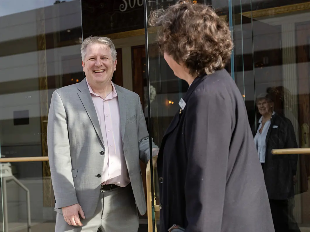 A female theater employee opens an entry door for a widely grinning Chad Whittington