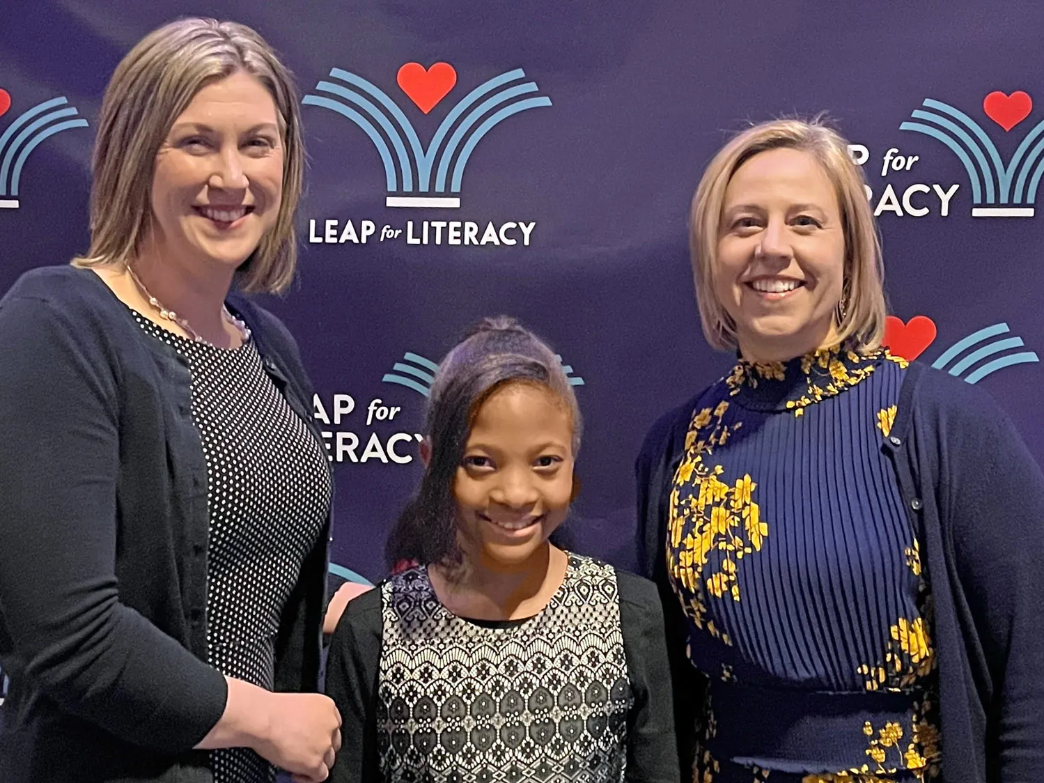 Amanda Waters Fields, left, proudly poses with one of her middle school students and another teacher as they attend an event for Leap for Literacy, a nonprofit that encourages reading by giving free books to children.