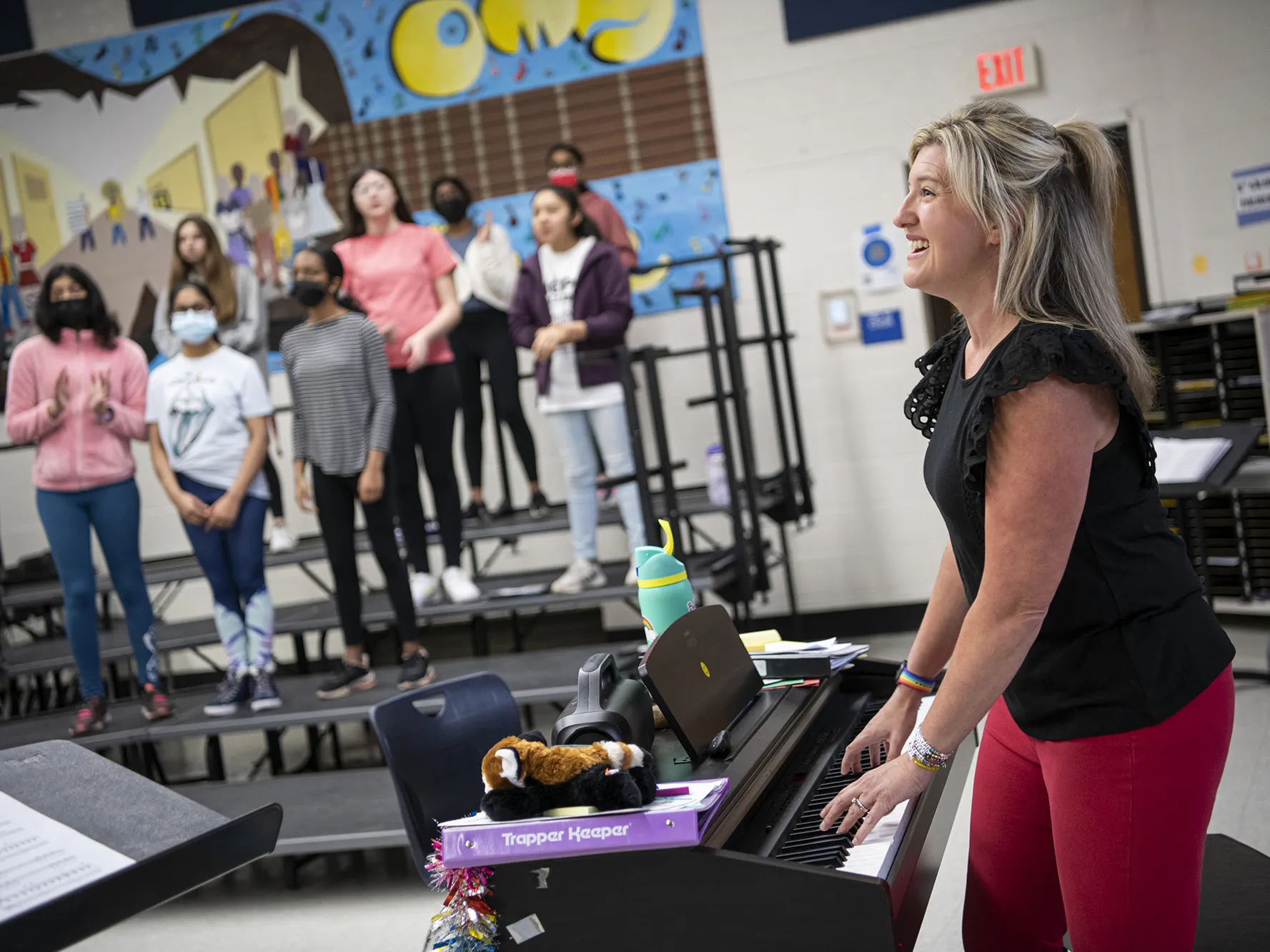 Katie Silcott plays electric piano in her classroom surrounded by students singing