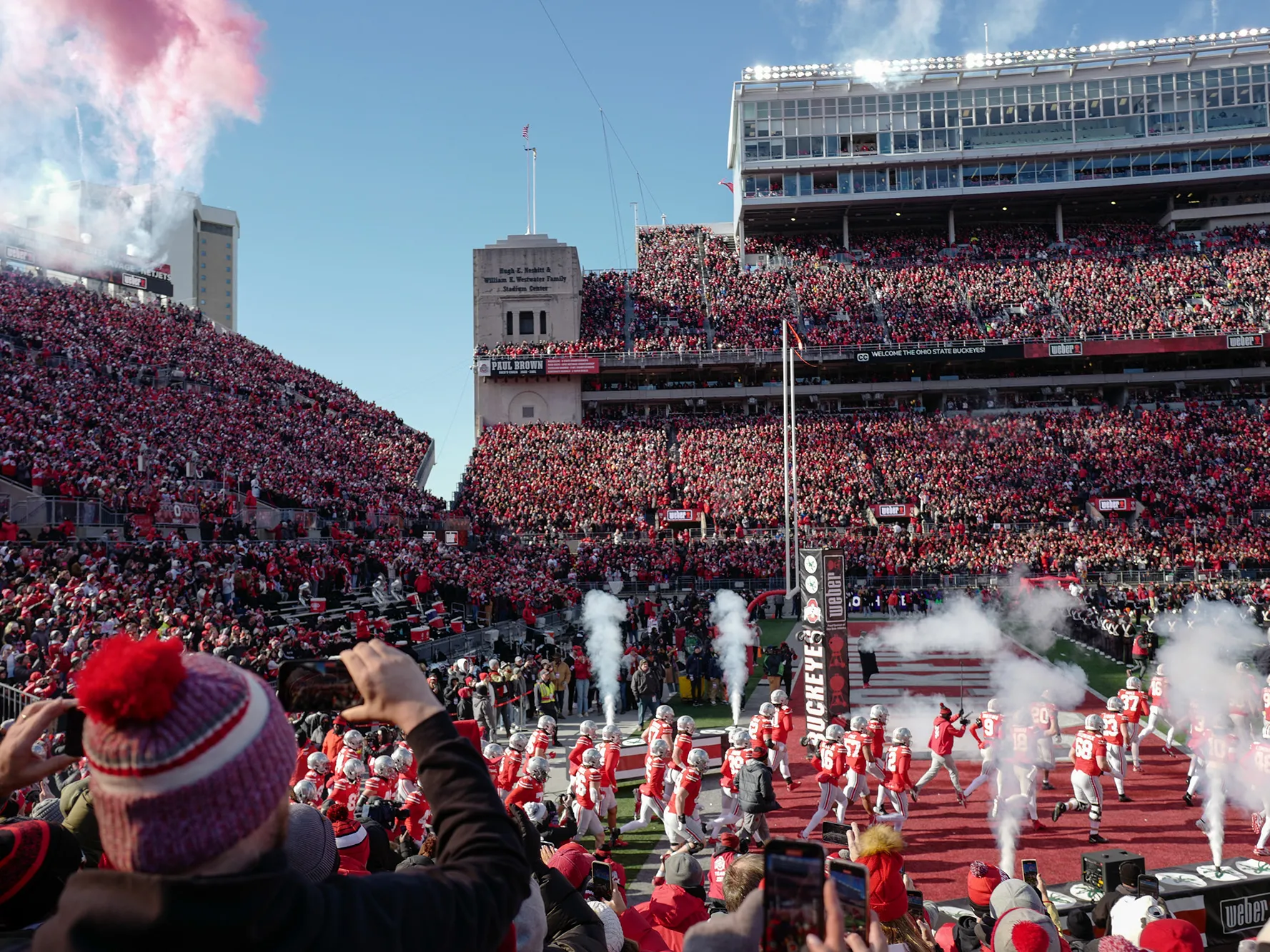 The Ohio State Buckeyes take the field inside Ohio Stadium before a huge crowd. There's a fan in every seat and smoke shoots up as the players come off the ramp