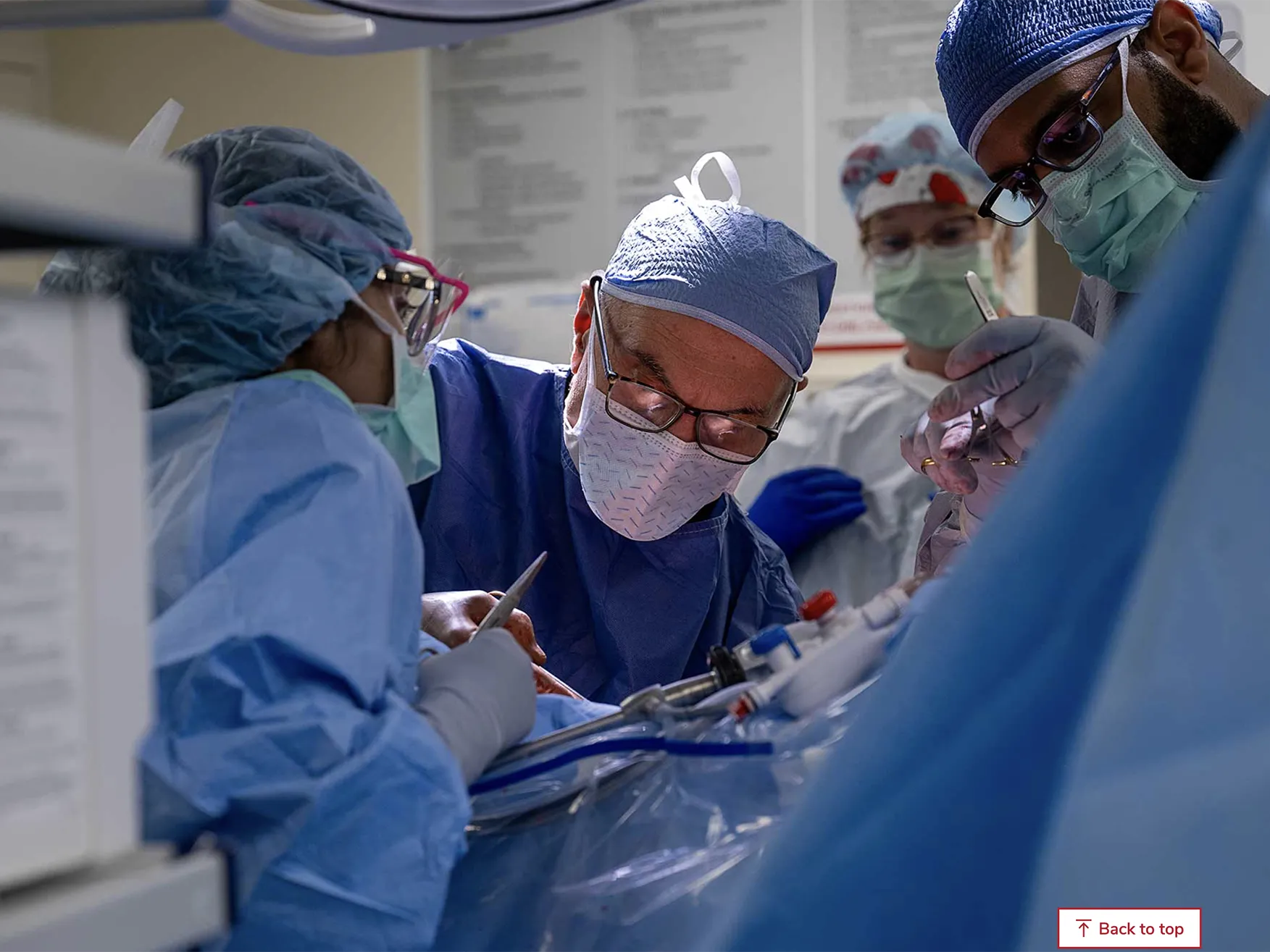 A team of Ohio State Wexner Medical Center employees works in the operating room to remove a donor's kidney. Ther are all suited up in scrubs, face masks and caps and lean over the patient, who cannot be seen.