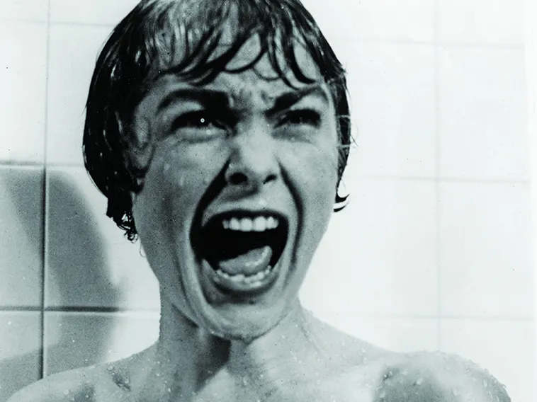 this black and white photo shows a white actress from a horror movie screams inside a shower stall