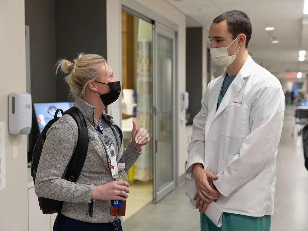 Aaron Craft talks to a nurse in a hallway of the Wexner Medical Center
