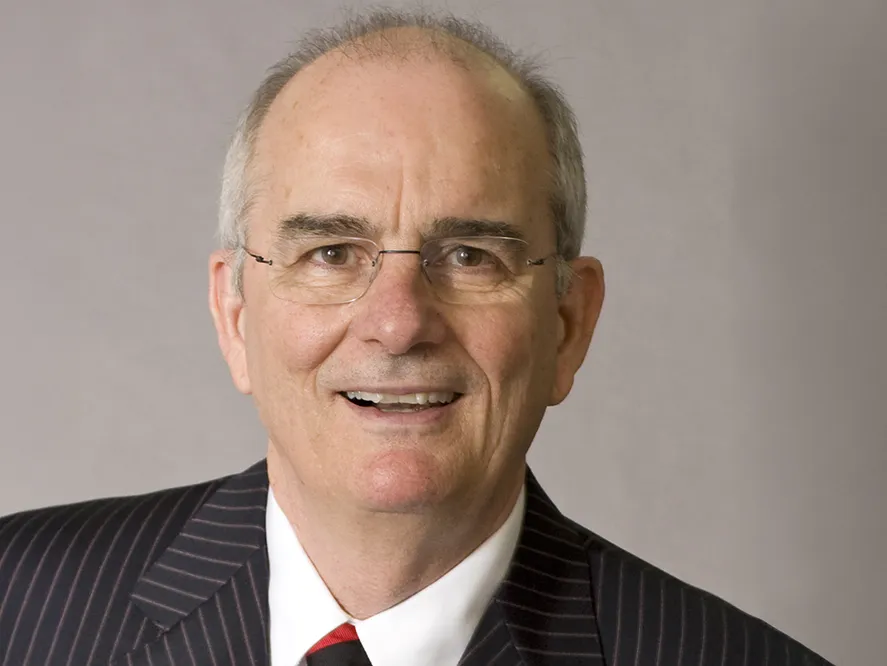 Gregory Williams wears glasses, a suit and an open mouthed smile. He looks like he's laughing as he poses for this formal portrait.