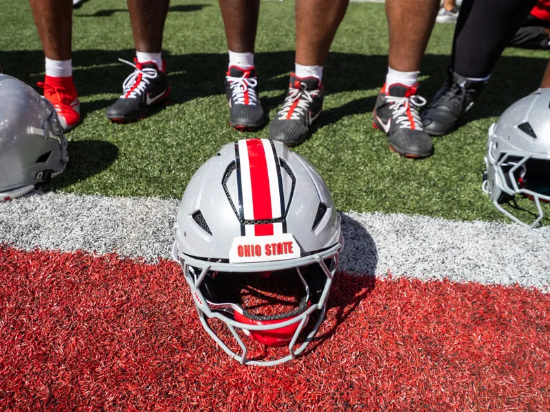 scarlet and gray football helmets sit on the field inside Ohio Stadium