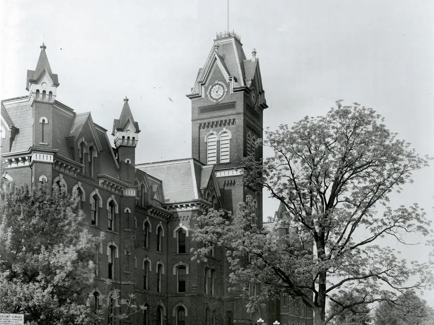 A black and white photo of the original University Hall building, including its tower