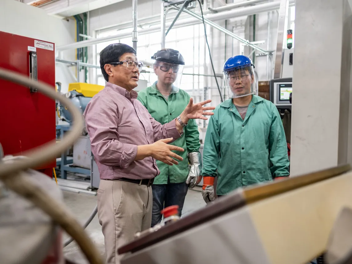 Alan Luo gestures as he works with grad students in his metals lab