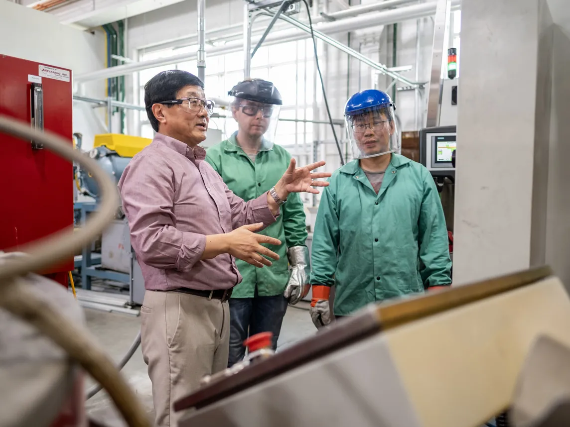 Alan Luo gestures as he works with grad students in his metals lab